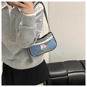Detail of blue denim and gingham shoulder bag with cherry embroidery and lace trim
