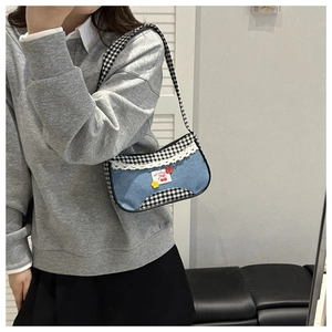 Detail of Y2K plaid shoulder bag with cherry patches and white lace trim detail