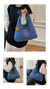 Detail of blue canvas tote bag showing white embroidery text and brown leather buckle charm