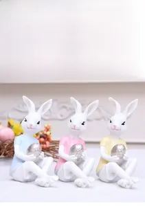 Detailed view of three resin Easter bunnies in blue, pink, and yellow holding silver eggs