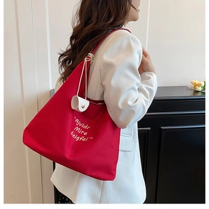 Close-up of red canvas tote bag with embroidery and a small white pouch accessory