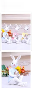 Detail of three colorful resin Easter bunnies holding metallic eggs for home decoration