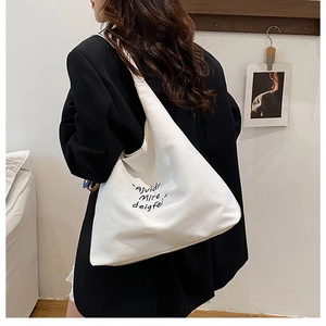 Detailed view of white canvas tote bag showing large capacity and black letter printing