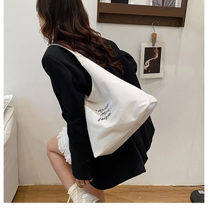 Detailed shot of white canvas tote bag featuring minimalist lettering and thick fabric