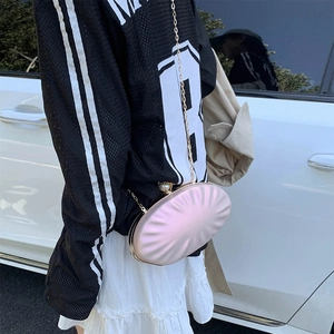 Pochette ovale rose pâle avec finition nacrée, fermoir perle géante et chaîne dorée