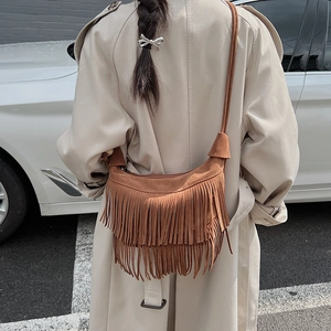 Borsa hobo in pelle scamosciata marrone con frange indossata da modella in trench