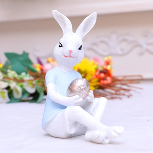 Easter resin rabbit figurine in blue shirt holding a silver spotted egg ornament