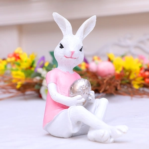 Cute Easter bunny resin figurine holding a silver metallic egg in a floral setting
