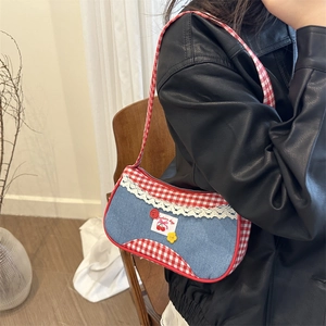 Checkered blue denim underarm bag with lace trim and cherry patch worn by model