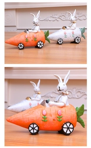 Detail view of two resin Easter bunnies driving carrot cars in orange and white colors