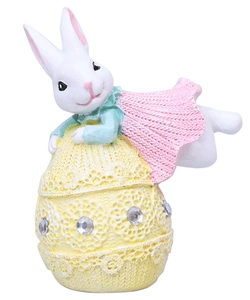 Detalle de conejo de Pascua con chal rosa sobre huevo amarillo con encaje y pedrería brillante