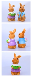 Detalle frontal y posterior de figuras de conejitos de Pascua de resina en trajes violeta y azul