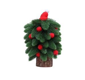 Mini sapin de Noël avec bonnet rouge et pompons sur un socle en bois naturel