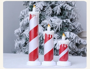 Close-up of three LED flameless candles with red stripes and snowy branch background