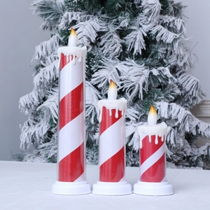Three-piece LED candy cane striped candles with faux melted wax on Christmas table