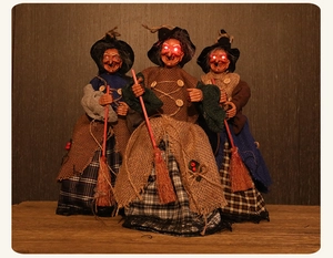 Detalle de tres brujas de Halloween con ojos LED rojos brillantes y trajes rústicos de tela