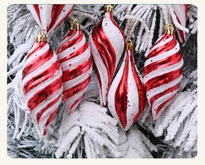 Details von rot-weißen Spiral-Weihnachtskugeln mit Schneetextur an einem Tannenzweig