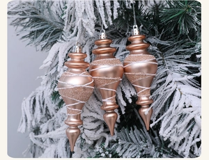 Champagne gold pinecone Christmas ornaments with white glitter spirals on snowy pine branch