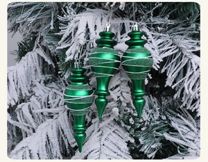Detail of green teardrop Christmas ornaments with white glitter on snow-covered tree branches