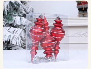 Three red Christmas finial ornaments with white glitter spirals in a clear retail gift box