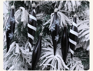 Detalle de adornos navideños en forma de cono sobre ramas de pino nevadas