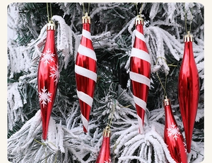 Detalle de adornos navideños de carámbanos rojos y blancos en una rama de abeto nevada