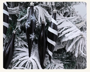 Detalle de carámbanos navideños negros brillantes con copos de nieve sobre un árbol nevado