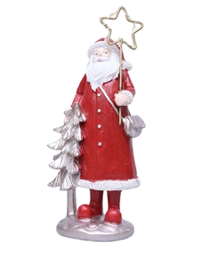 Detail of resin Santa figurine holding a star wand beside a silver holiday tree