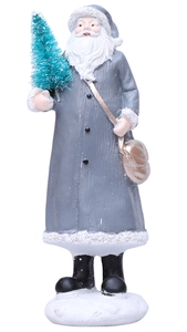 Detail of Santa figurine in grey robe holding a green tree on a snowy white base