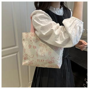Detail showing colorful cartoon graffiti prints and pink straps on the white canvas tote bag