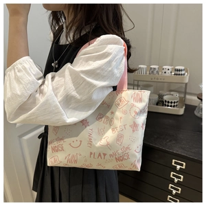 Close-up of a white tote bag with pink graffiti patterns and stylish pink woven handles