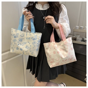 Detail of canvas tote bags with vibrant cartoon graffiti and colored handles for daily use