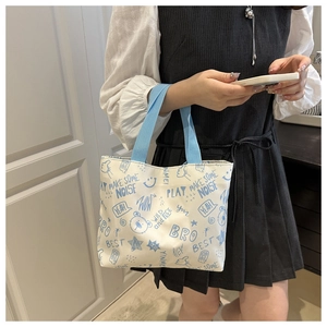 Detail of canvas tote bag with blue graffiti print and ribbon handle on a female model