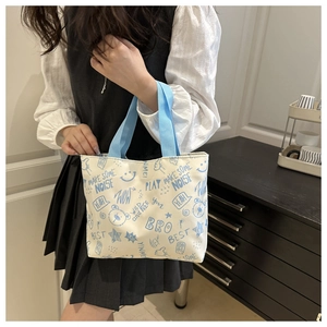Detail of white canvas tote bag featuring blue cartoon bear print and blue fabric handles