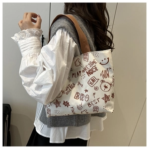 Detail of canvas tote bag with retro graffiti prints and brown shoulder straps