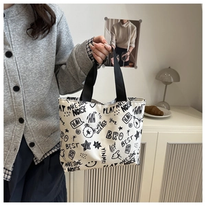 Detailed view of white canvas tote bag with black graffiti art and thick webbing handles