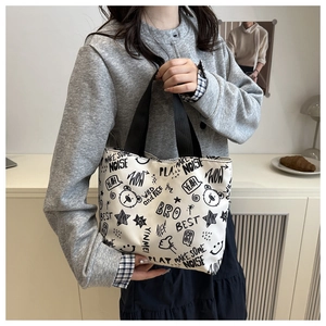 Detail of off-white canvas tote bag featuring graffiti text and cartoon bear pattern
