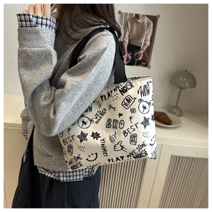 Detailed view of canvas tote bag featuring artistic black graffiti and sturdy nylon handles