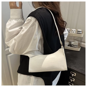 Detail of white crocodile texture faux leather shoulder bag worn by a model