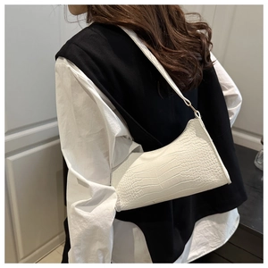 Close-up of white crocodile pattern baguette bag showing faux leather texture and side metal ring