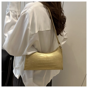 Close-up of golden crocodile pattern shoulder bag with sleek zipper and thin strap