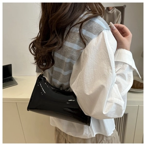 Detail of black glossy patent leather shoulder bag with sleek rectangular shape and strap