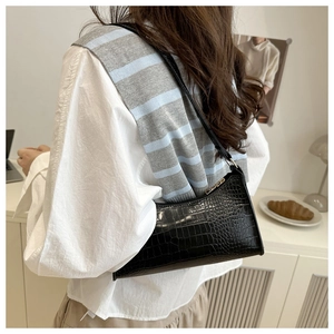 Close-up of black crocodile pattern faux leather shoulder bag with glossy finish