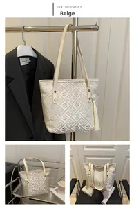 Detail view of beige tote bag with geometric jacquard pattern and long tassel charms