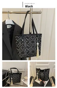 Detail view of black tote bag with silver geometric patterns and chic long tassel pendant