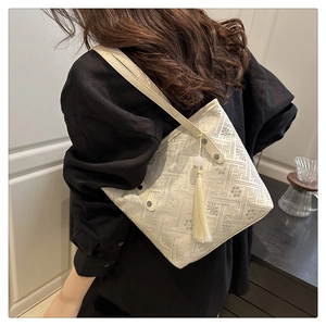Dettaglio borsa a secchiello jacquard beige ricamata con nappe e sottili tracolle in pelle