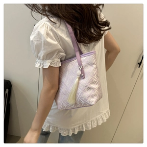 Dettaglio della borsa tote lavanda con ricamo cinese e ciondolo a nappa color crema elegante