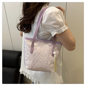 Dettaglio della borsa tote jacquard lilla con nappa elegante e ciondolo di perla