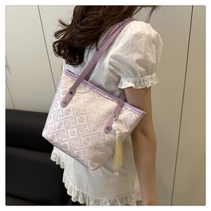 Dettaglio della mini borsa tote jacquard lavanda con motivo tradizionale e nappa bianca