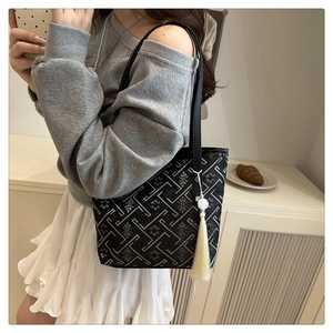 Dettaglio borsa tote con motivo geometrico e nappa color crema indossata da una modella
